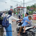mahasiswa Teknik Industri ITN Malang memberikan bungkusan berisi makanan ke pengendara sepeda motor